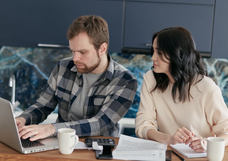 A couple working together on financial planning at home, using a laptop and paperwork